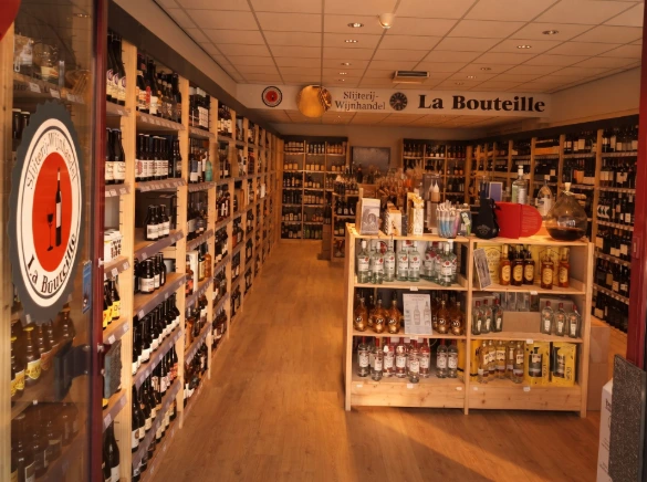 Interieur van La Bouteille slijterij en wijnhandel met schappen vol drankflessen - La Bouteille groeit met Newconomie