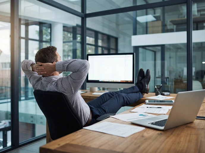 Ondernemer leunt rustig achterover met zijn voeten op bureau terwijl zijn administratie en facturatie verwerkt worden. Administratieve ondersteuning en facturatie uitbesteden via Odoo partner Newconomie